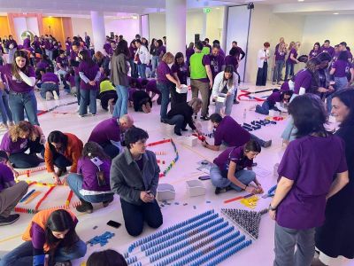 Medewerkers van Danone in paarse T-shirts zetten samen dominostenen op in een hotelzaal in M&aacute;laga
