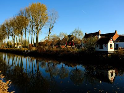 Autumn trees and houses reflected in the canal of Damme