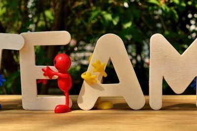 Lettres en bois formant le mot TEAM, soutenues ensemble par de petites figurines